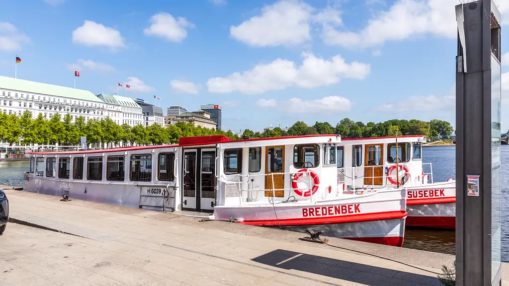 Historische Alsterdampfer Bredenbek und Susebek liegen am Anleger Jungfernstieg, dahinter Binnenalster und Hotel Vier Jahreszeiten, sonnig