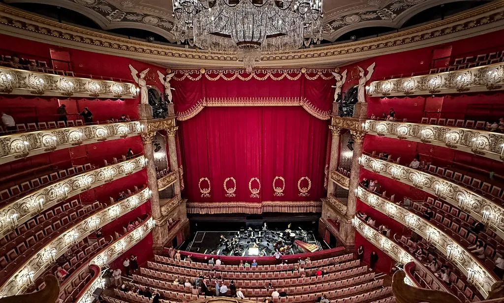 Zuschauerraum des Nationaltheaters von oben: roter Vorhang, Logenränge, Kronleuchter und Orchestergraben