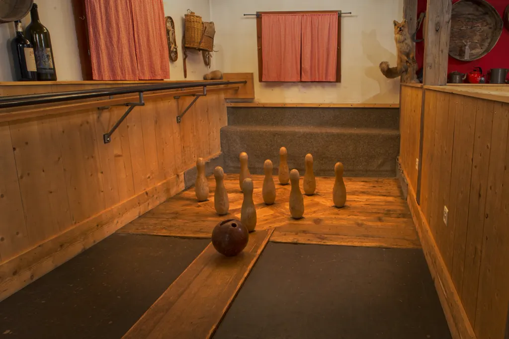Traditionelle Holz-Kegelbahn in einem eigenen, holzvertäfelten Raum: neun Kegel in Rautenaufstellung, davor eine Kugel auf der Bohle, warmes Licht.