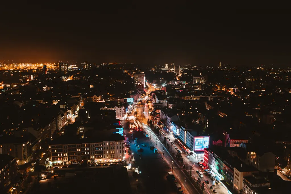 Nächtlicher Blick von oben auf die beleuchtete Reeperbahn und den Spielbudenplatz in St. Pauli, links hinten die Lichter des Hafens.