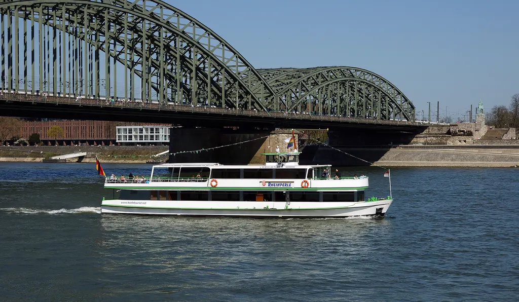 Rundfahrtschiff RheinPerle von KölnTourist fährt vor der Hohenzollernbrücke, blauer Himmel