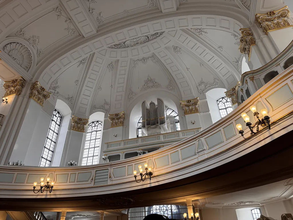 Kirchenraum des Michel: weiß-goldene Emporen, Stuckdecke und C.-P.-E.-Bach-Orgel, warm leuchtende Wandlampen