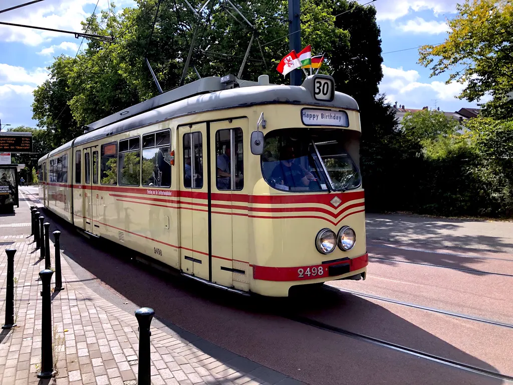 Historischer Speisewagen 2498 der Rheinbahn mit Schild „Happy Birthday“, Sonder-Liniennummer 30 und Fähnchen, sonnig in Benrath