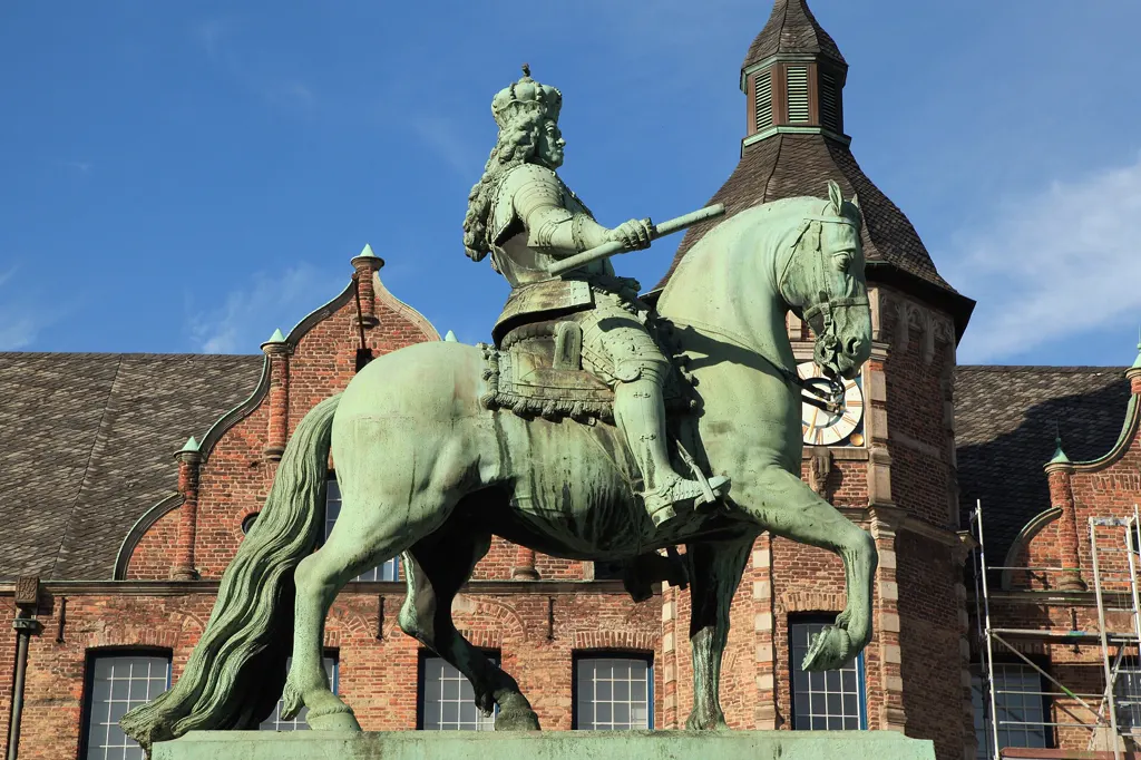 Reiterstandbild des Kurfürsten Jan Wellem auf dem Düsseldorfer Marktplatz vor dem Rathaus mit Uhrturm unter blauem Himmel.